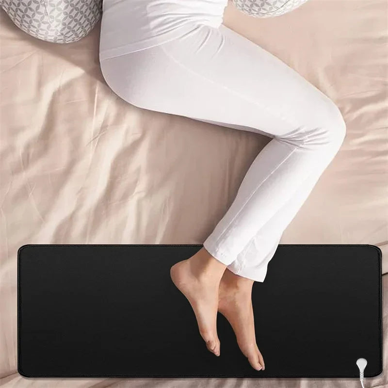 Feet resting on the grounding mat at the foot of a bed